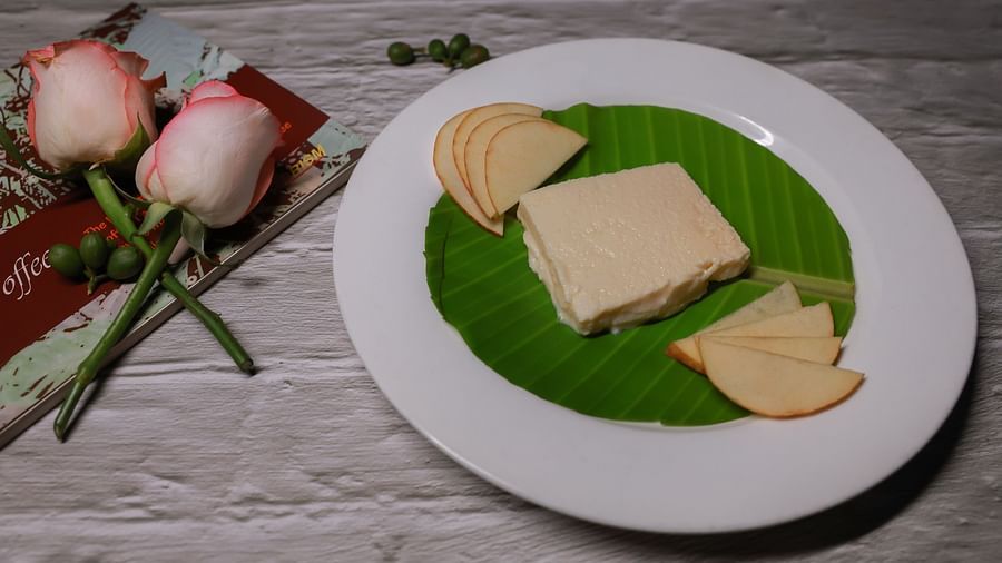A dessert dish with apple slices next to roses at The canopy, Capitol Village Resort, Madikeri