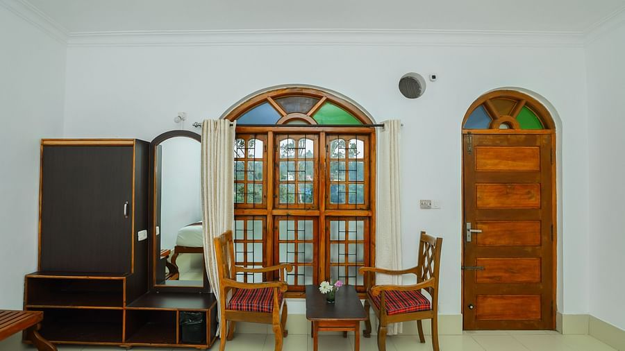 Chairs, table, wardrobe and entrance to the room - Capitol Village Resort, Madikeri