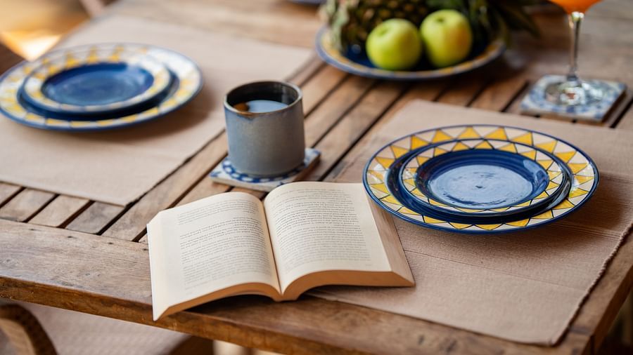Image of an open book lying on the dining table next to dining plates