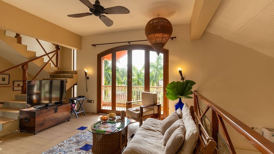 Image of a room featuring a cosy sofa and a coffee table along with a TV in front as the door to the balcony is shut 