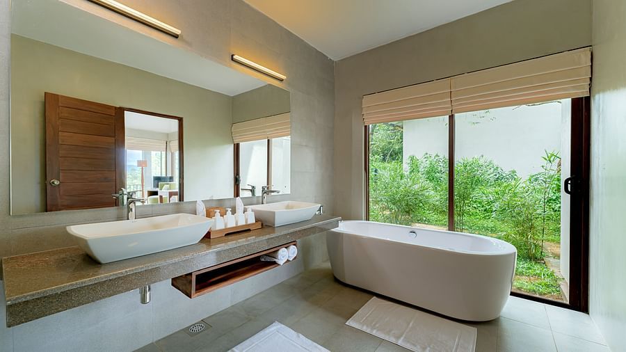 A bathtub, mirror and sink in a bathroom with huge glass windows | Celestial Hills, Kandy