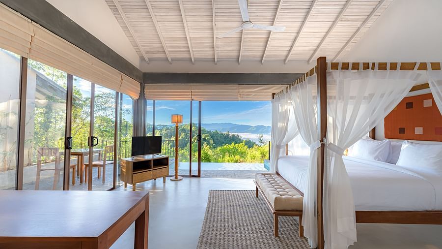 A full view of a room with a bed, table, TV and a balcony | Celestial Hills, Villas & Suites, Kandy