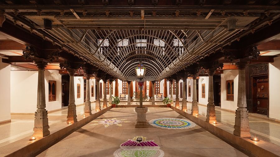 Interior of Chidambara Vilas Resort showing a spacious, traditional Indian assembly hall with ornate wooden architecture and stained glass