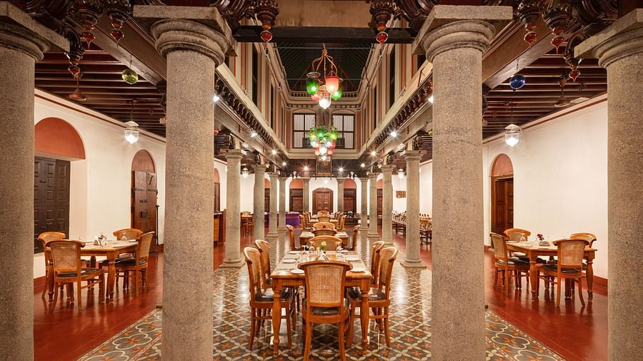 Elegant dining hall with vintage furniture and colorful floor tiles under a grand wooden ceiling at Chidambara Vilas Resort