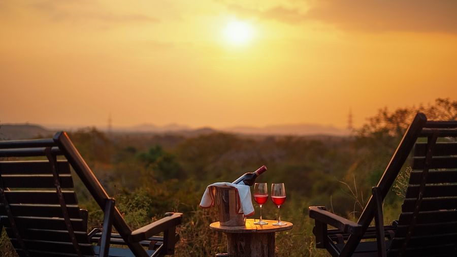 a close up shot of a table with glasses and bottles on it and chairs next to it and the sun setting in the background - Chunda Shikar Oudi, Udaipur.