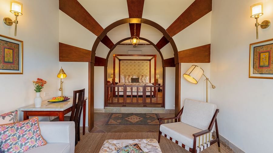 a king bed in the foreground and sofas and coffee table inside the villa - Chunda Shikar Oudi