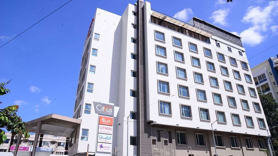 A modern multi-storey hotel building with large windows and signage, set against a bright blue sky. - Citrus Classic, Outer Ring Road, Bangalore