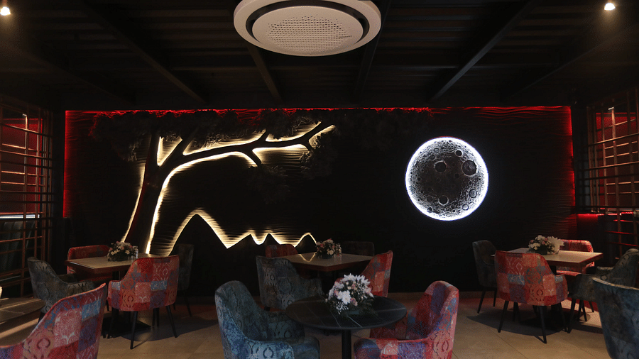 Vibrant dining area with patterned chairs and striking wall art of a tree and glowing moon, creating a cosy ambience - Nysa Skybar