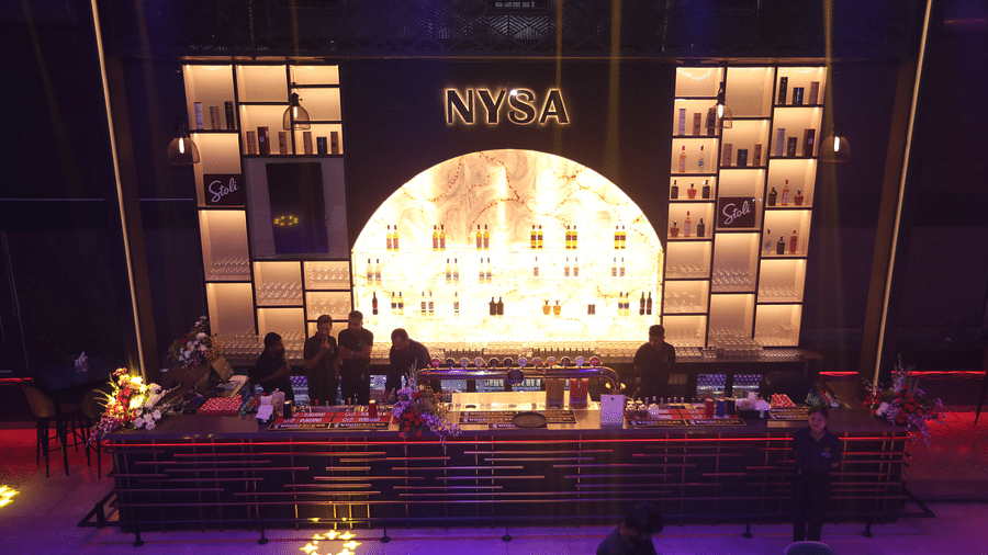 Stylish bar with illuminated shelves, a sleek counter, and staff preparing drinks in a vibrant setting - Nysa Skybar, Bengaluru