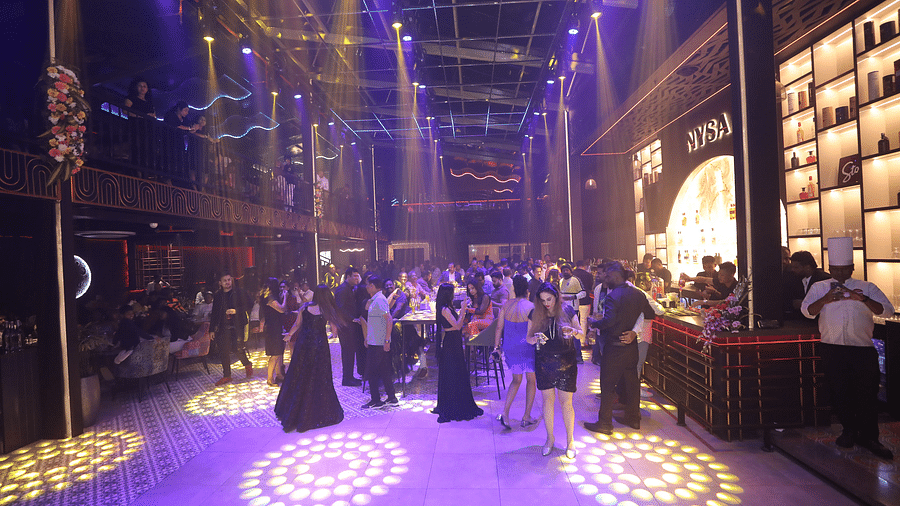 Vibrant party scene at Nysa Skybar with guests mingling and dancing under colourful lights, showcasing a lively atmosphere filled with energy and excitement.