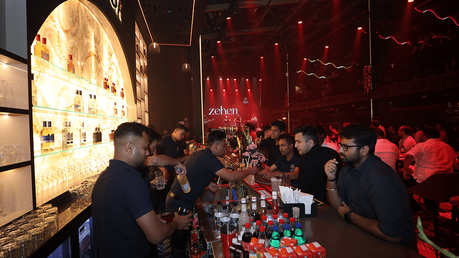 Energetic bar scene with attentive bartenders serving drinks against a vibrant backdrop, illuminated by red lights, creating a lively atmosphere for guests - Nysa Skybar