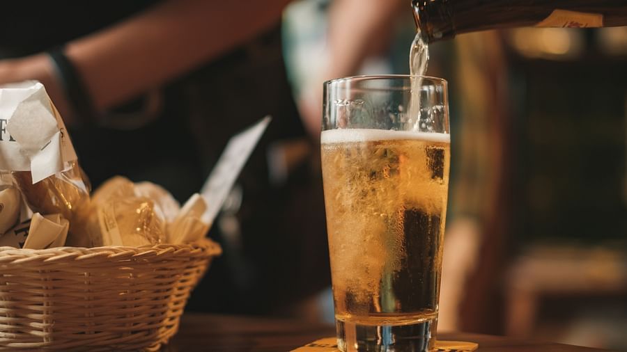 A beer being poured to a tall glass with accompaniments on the side