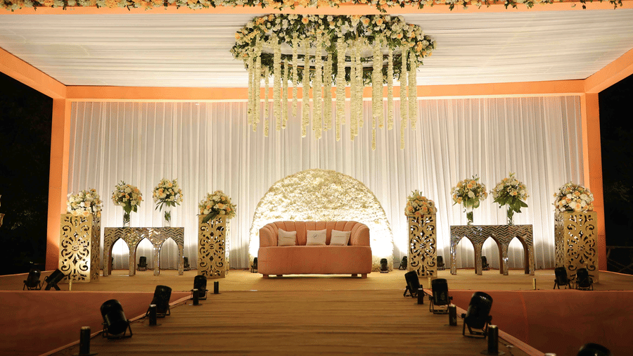 An elegantly designed wedding stage featuring cascading floral arrangements, decorative pillars, ambient lighting, and a statement seating area prepared for the ceremony and reception | Clarks Amer, Jaipur
