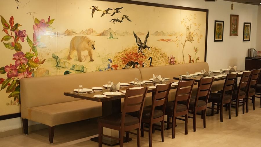 A restaurant with seating arrangements, ceiling lights and wall paintings at Clarks Collection, Bhavnagar