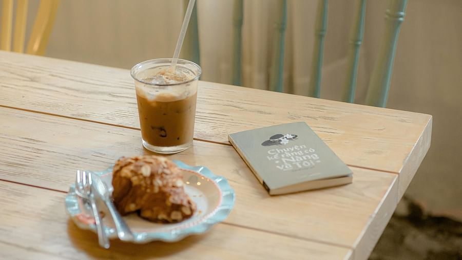 A rustic wooden table holds a glass of iced coffee and a pastry, perfect for a relaxed moment.