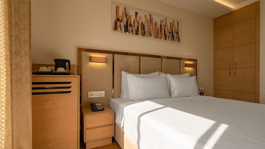 A hotel room with a king size bed, a flat-screen TV, a work desk, and a large window with natural light - Clarks Inn, Indore.
