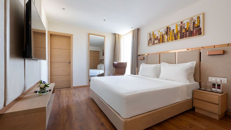 Hotel bedroom with a king-size bed, a flat-screen TV, a work desk, and a comfortable armchair - Clarks Inn, Indore