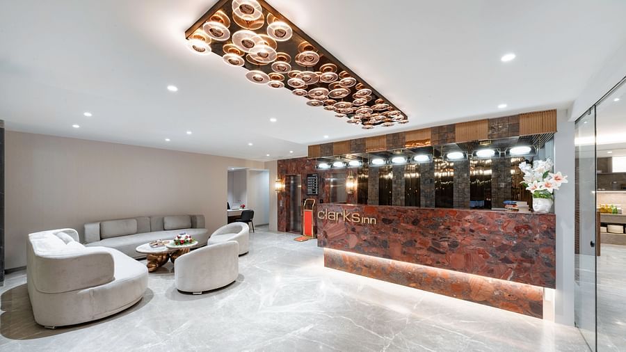 Modern hotel lobby with a stylish reception desk, plush seating, and a unique chandelier -  Clarks Inn, Indore