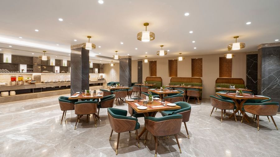Spacious restaurant with a large buffet table and tables with chairs - Clarks Inn, Indore