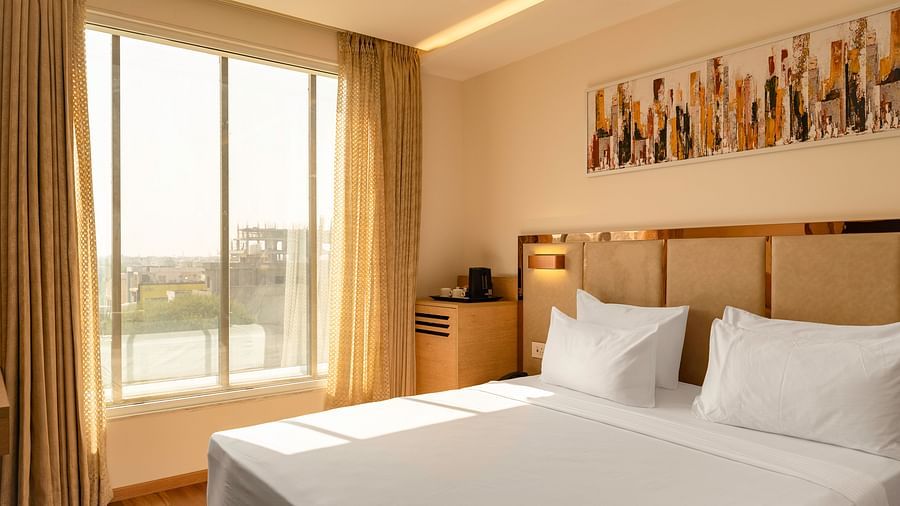 Spacious and well-lit hotel room with a comfortable bed and modern furnishings -Clarks Inn, Indore