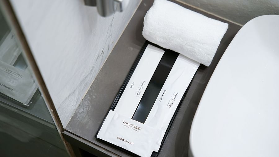 Close-up of a hotel bathroom counter with toiletries and rolled towels - Clarks Inn, Indore