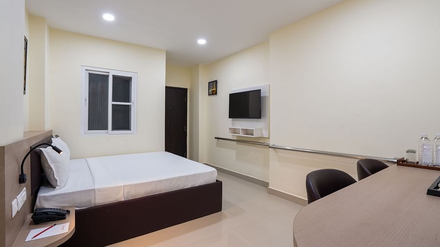 Accessible room at Clarks Inn, Near Kainchi Dham features a double bed with white linens, a wall-mounted television, a desk with chairs, and a window with white frames.