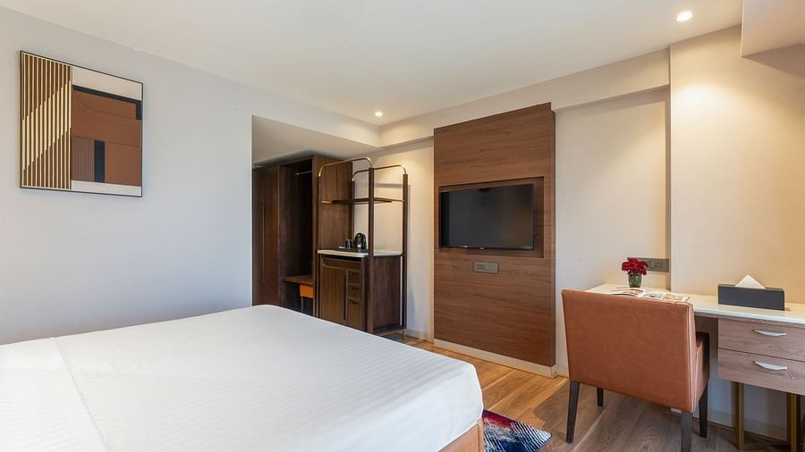 Cosy hotel room with king bed, TV, writing desk and wardrobe in view at Clarks Inn Suites, Hyderabad
