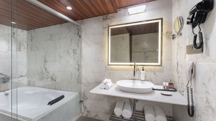 Modern bathroom with marble walls, backlit mirror, countertop basin, and towel rack at Clarks Inn Suites, Hyderabad