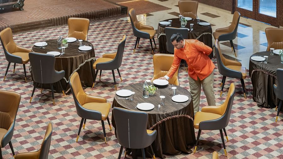 Staff member arranging round tables with tableware in banquet hall at Clarks Inn Suites, Hyderabad