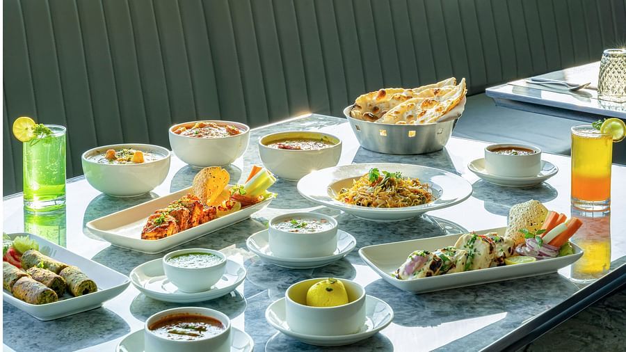 Feast spread on a marble table featuring soups, rice, curries, breads and sauces in white bowls at Clarks Inn Suites, Hyderabad