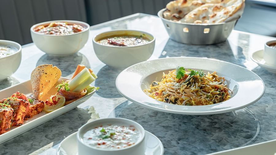 Overhead view of marble tabletop laden with naan, curry bowls, rice, chutneys, and kebabs at Clarks Inn Suites, Hyderabad
