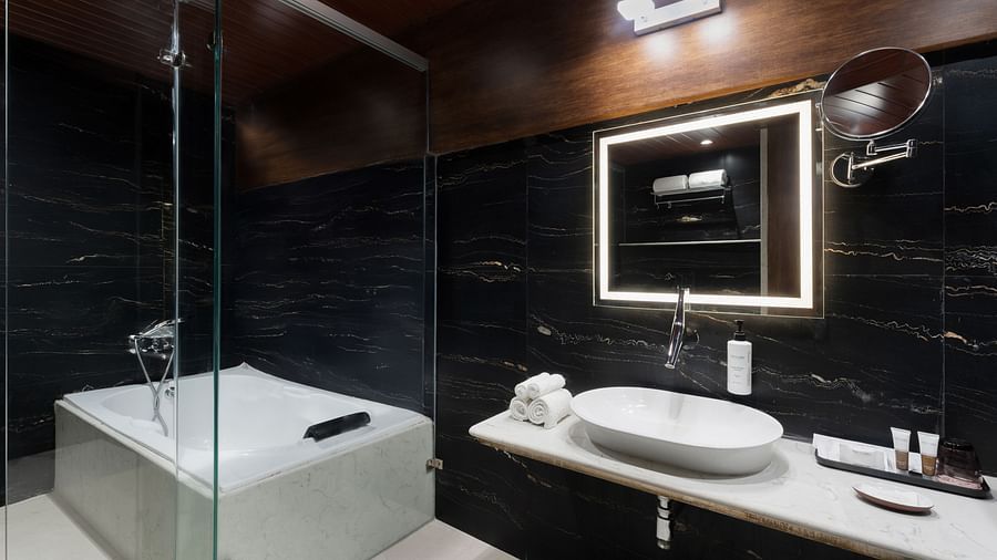  Stylish bathroom featuring a bathtub, glass partition, and illuminated mirror above at Clarks Inn Suites, Hyderabad