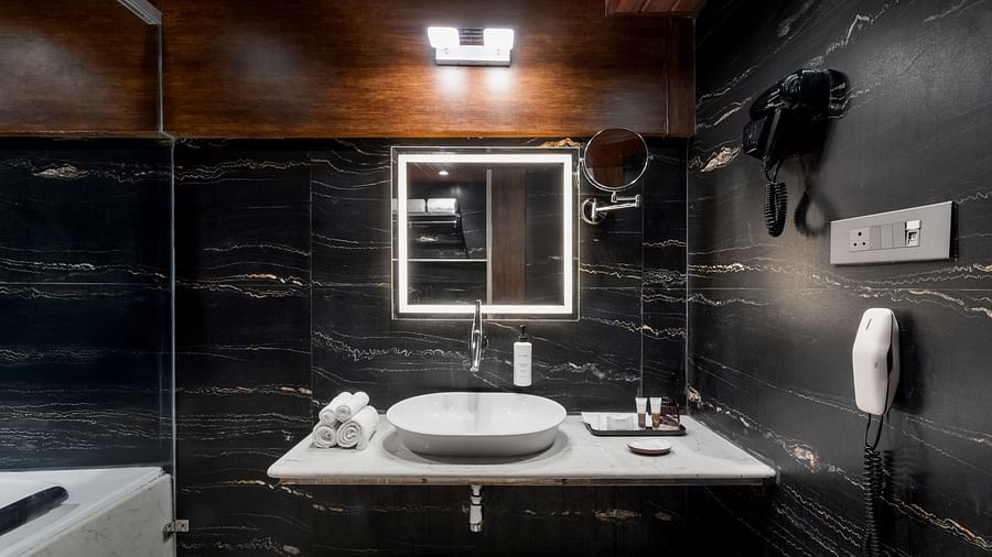  Modern bathroom with black marble walls, LED mirror, and white countertop with basin sink at Clarks Inn Suites, Hyderabad