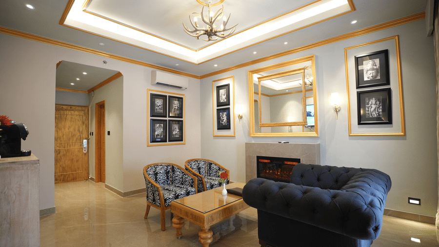 An Executive Suite living area at Clarks Khajuraho with cushioned seating, a center table, framed wall art, and a well-lit ceiling design.