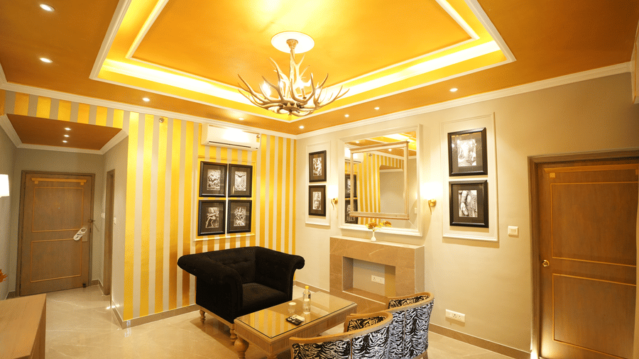 An Executive Suite lounge area at Clarks Khajuraho featuring a seating arrangement, a wall mirror, decorative panels, and an entry door.