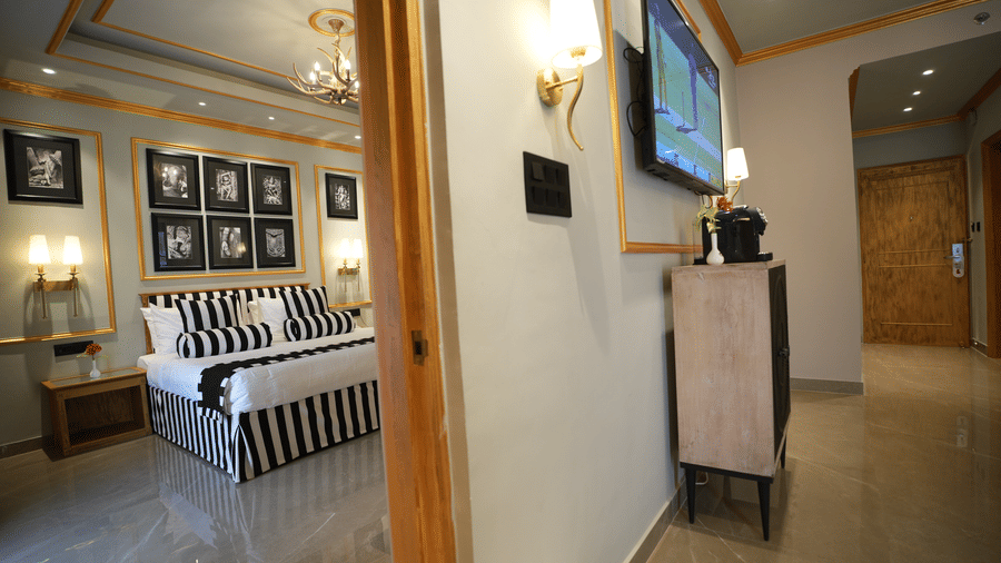 An Executive Suite view at Clarks Khajuraho showing a corridor leading into a bedroom, with framed artwork on the walls and a glimpse of the bed setup.