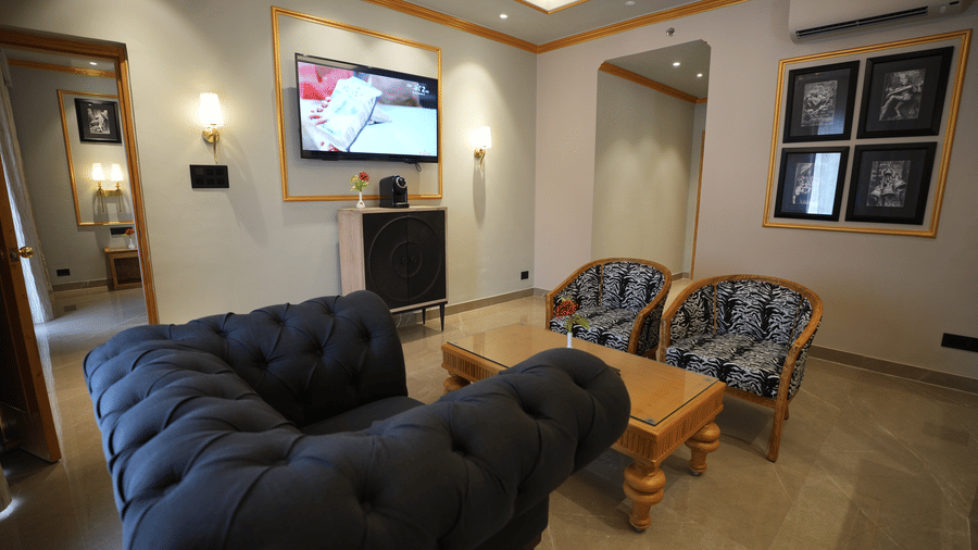 An Executive Suite living room at Clarks Khajuraho with sofas, a center table, a wall-mounted television, and framed artwork.