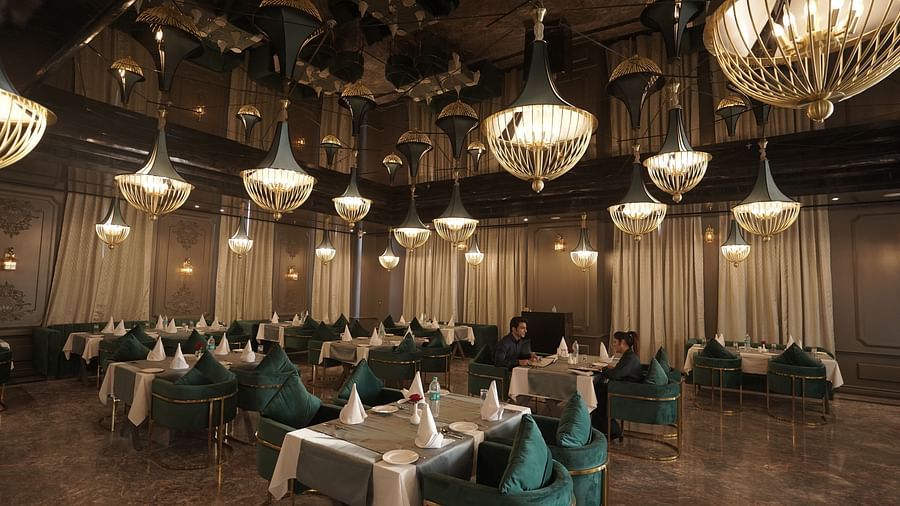 restaurant with tables and chairs having round lights on the ceiling at Classic Sapphire by Ananta