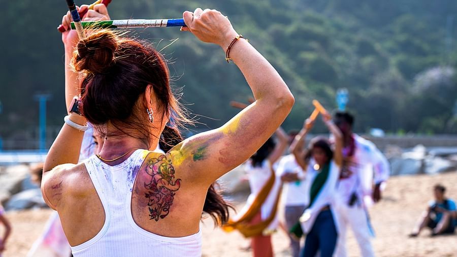 A close up shot of a woman dancing and and other people playing on a sandy beach.