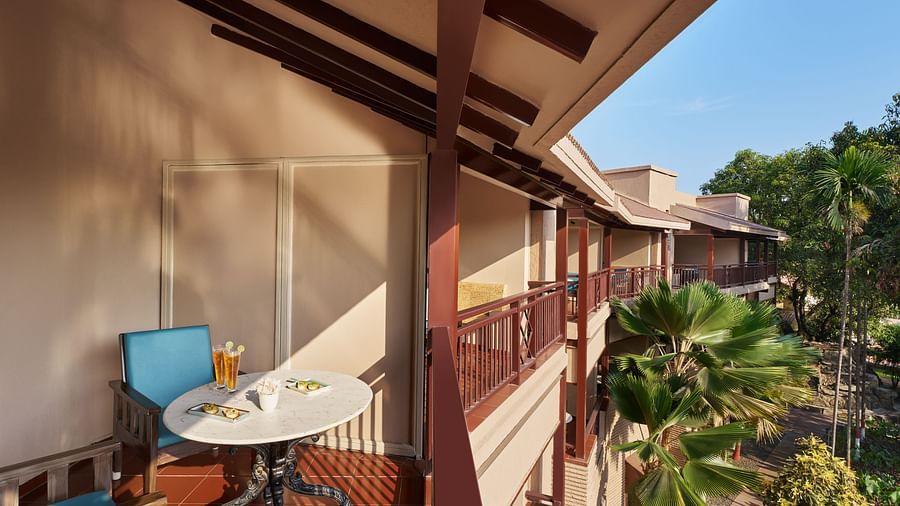 A private balcony of Executive Room with Balcony at DGV Resort by Treat, Silvassa, featuring a small table with drinks and snacks, overlooking lush tropical greenery