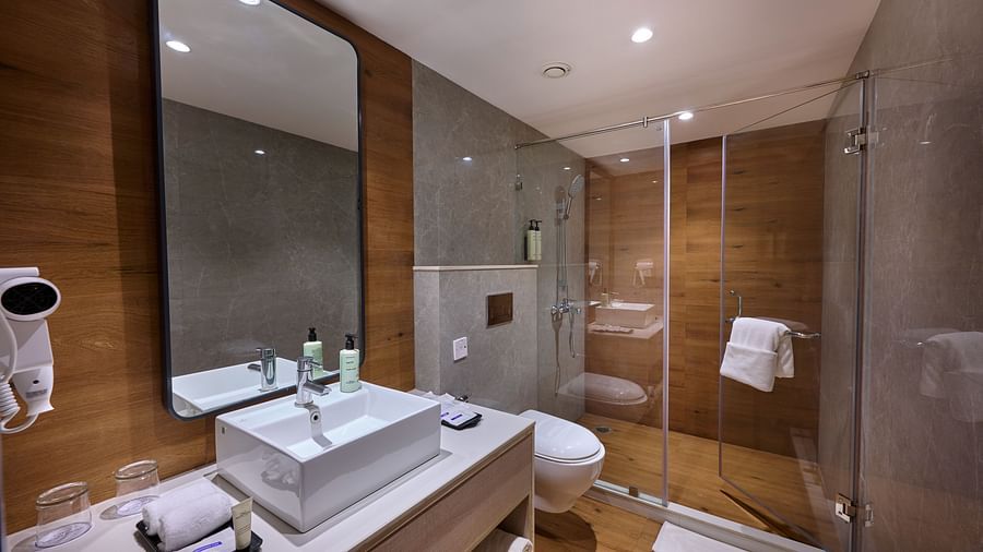 A hotel bathroom with a large sink, wall-mounted mirror and a separate shower cubicle