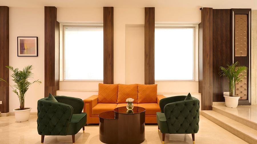 A waiting area with comfy orange sofas and green chairs placed around a coffee table