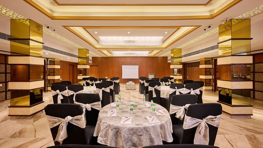 An image of the royal hall with round tables, ambient lighting and a wall mounted screen in front