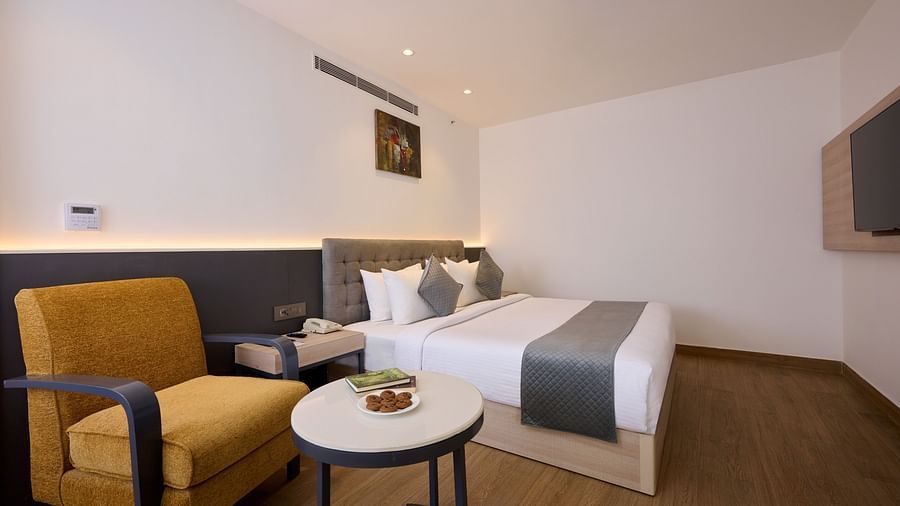 A side angle shot of a hotel room with a bed, a chair, a coffee table and ambient lighting