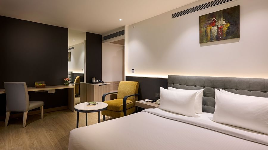 An image showcasing a bed in the foreground with a seating area positioned behind it