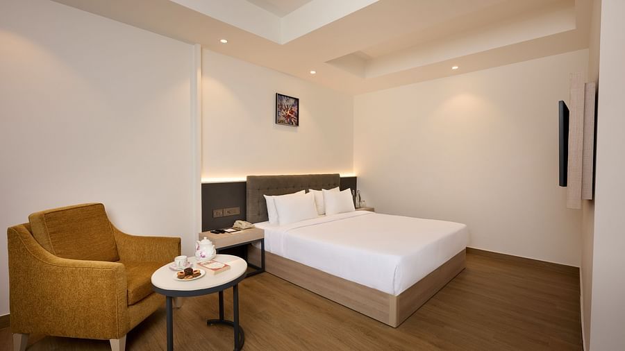A close up shot of a hotel room with a bed, a chair, a coffee table and ambient lighting