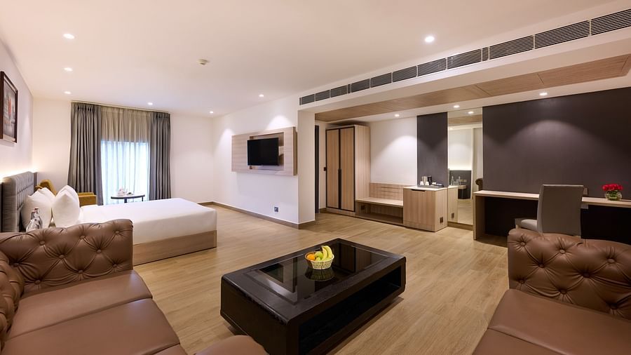 A hotel room with a large bed, comfortable sofas and a television