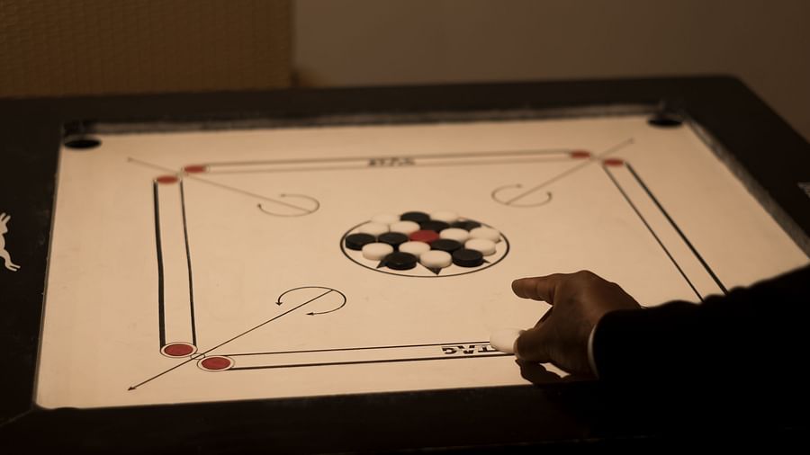  A focused shot of a hand expertly playing carrom on a well-lit board, highlighting the indoor game options available for guests - Digantaa Resort in Mukteshwar