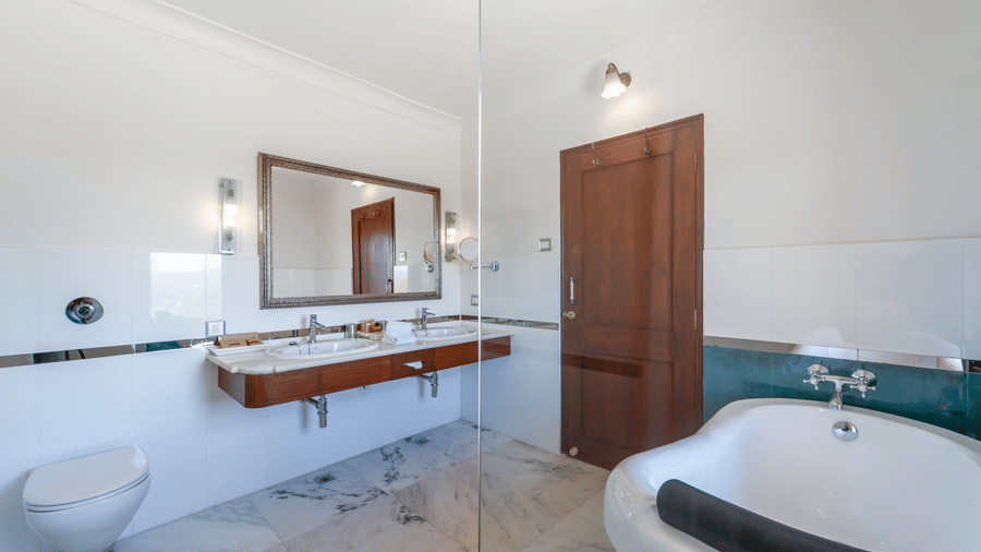 A bright, contemporary bathroom featuring a white soaking tub, marble floors, and a glass-enclosed shower - Fateh Garh, Udaipur