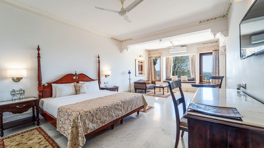 A perspective shot of a luxury suite showing the bed and a large window looking out over the Udaipur landscape - Fateh Garh, Udaipur